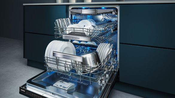 A dishwasher with fully opened door installed in a dark blue cabinet.