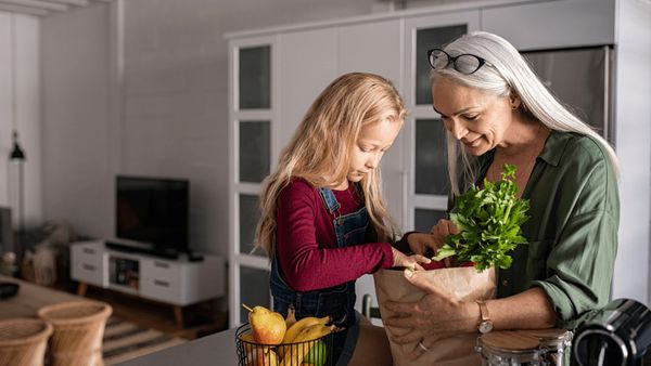 Μια ηλικιωμένη γυναίκα κρατάει λαχανικά δίπλα σε ένα μικρό κορίτσι