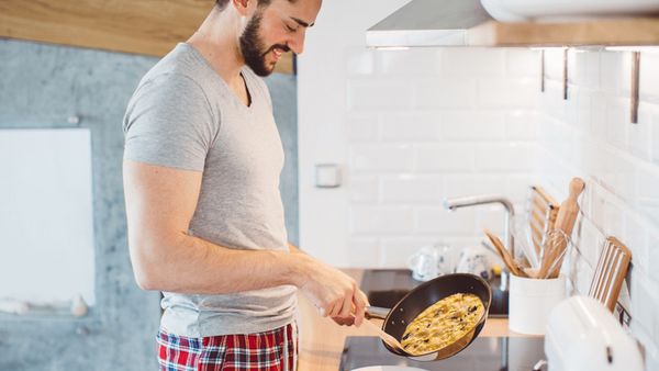 A man in boxer shorts frying an omelettete.