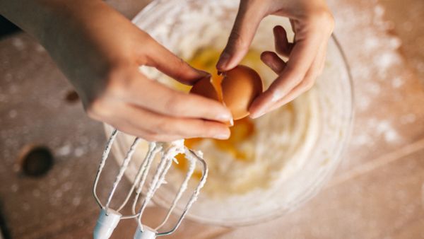 Adding egg to a mixing bowl