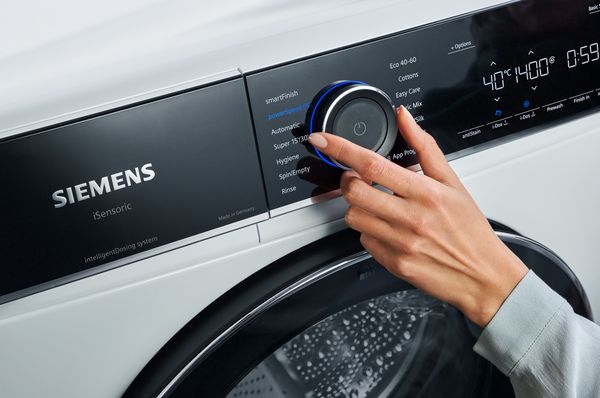 Nahaufnahme des digitalen Bedienfelds einer wei&szlig;en Siemens Frontlader‑Waschmaschine mit Drehw&auml;hler und beleuchtetem LED‑Display.