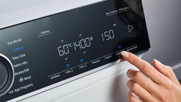 Eine Person bedient das Display einer Siemens iQ700 Waschmaschine.