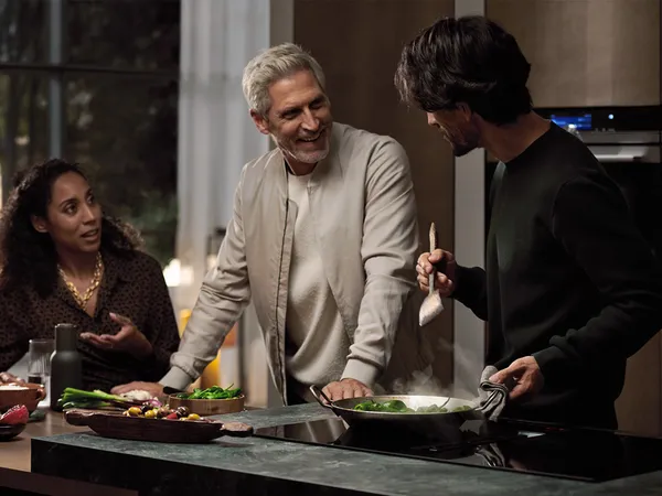 Family members preparing and enjoying a meal together in a kitchen setting.
