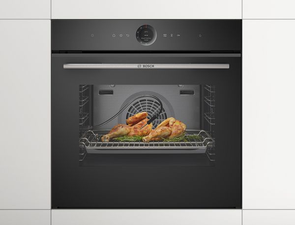 Ein knuspriges H&auml;hnchen vor einem Bosch Backofen in einer modernen wei&szlig;en K&uuml;che.