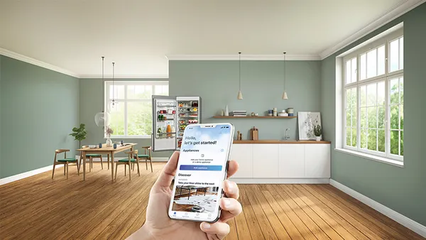 Smartphone mit der Home Connect App vor ge&ouml;ffnetem K&uuml;hlschrank