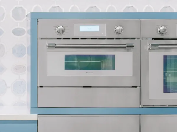 Four à cuisson rapide Thermador avec tiroir-réchaud dans une cuisine bleue à tuiles géométriques 