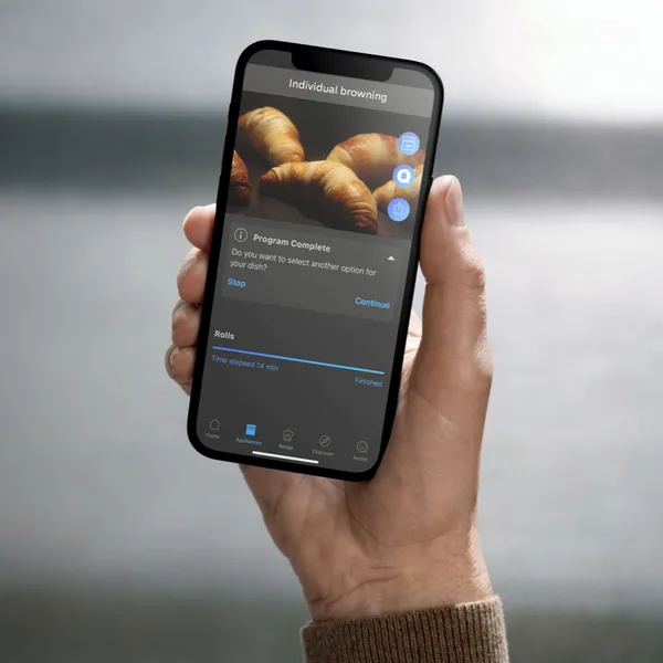 Smartphone displaying image of croissants, hand holding device against blurred background.