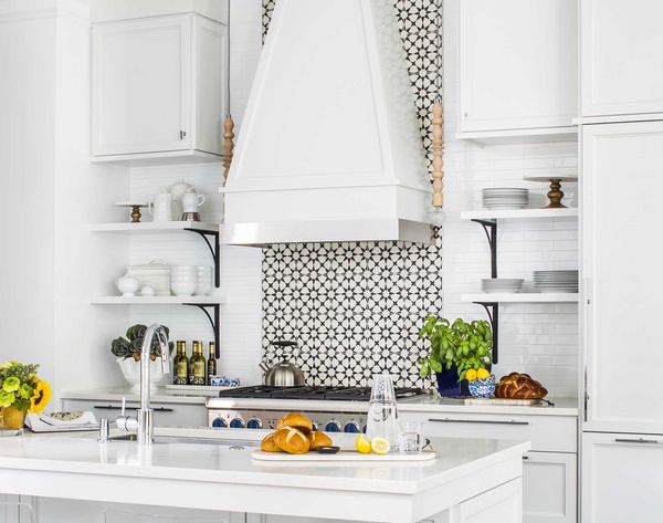 White kitchen with blue knobs on Thermador range and white hood-floral backsplash