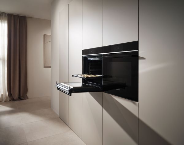 Cocina moderna con horno incorporado, armarios blancos minimalistas y ventana cortina.