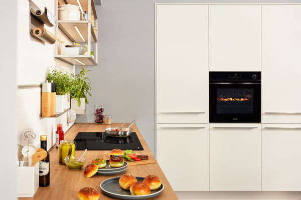 Helle Küche mit Constructa Backofen und Burger-Zutaten auf der Holz-Arbeitsplatte.