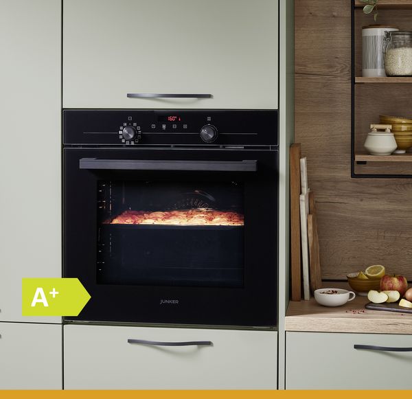Schwarzer Backofen in grünem Schrank, der Lebensmittel bei 160 °C backt und eine Energieeffizienzklasse von A+ aufweist. 
