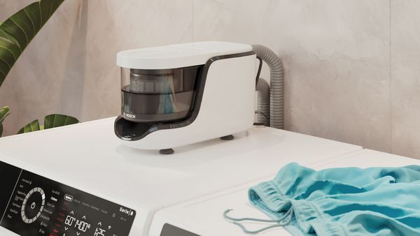 Seitenansicht eines Bosch Mikroplastikfilters auf einer Waschmaschine, daneben blaue Shorts.