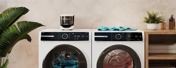 A bright laundry room with plants and a Bosch Microplastic Filter standing on top of a washing machine.
