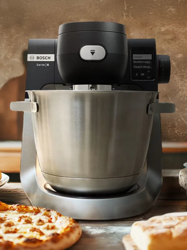 Planetaria da cucina Bosch in primo piano con una pizza e una focaccia davanti