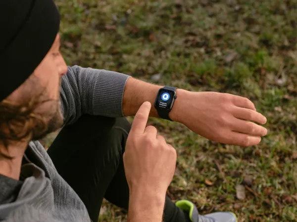 Man at the park taking a looking at his smartwatch on his home connect app