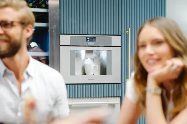 man and woman talking overlooking coffee machine