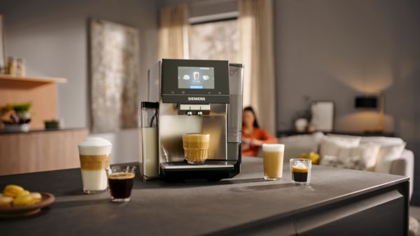 An EQ700 on a counter with a Flat White under the dispenser surrounded by various coffee beverages.