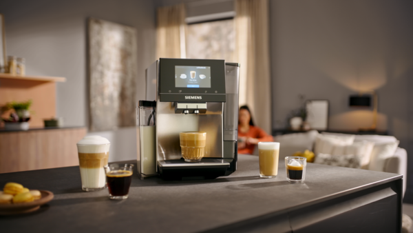 An EQ700 on a counter with a Flat White under the dispenser surrounded by various coffee beverages. 