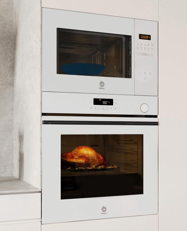Cocina moderna con un horno blanco, un pavo asado en su interior y varios utensilios de madera en un soporte sobre la encimera junto a un trapo azul.