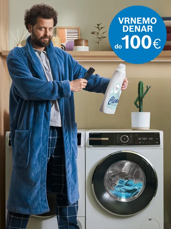 Moški v kopalnem plašču drži detergent in stoji pred pralnim strojem Bosch.