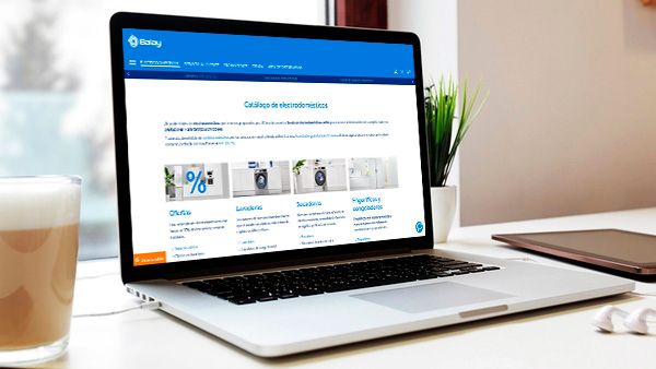 Portátil sobre una mesa mostrando una tienda en línea de accesorios y repuestos, con imágenes de productos y una planta cerca.