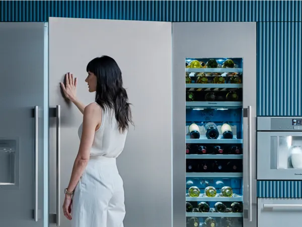 woman closing opening refrigerator column in blue kitchen