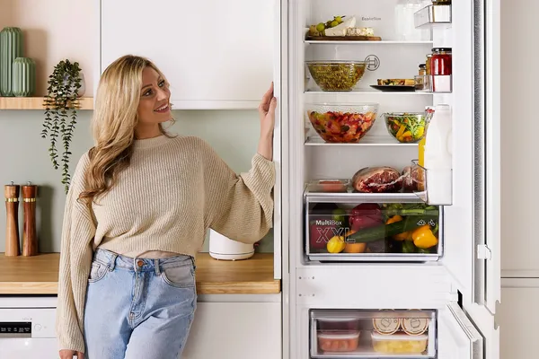 Woman stood next to open fridge freezer