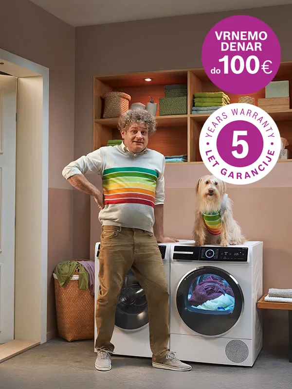 Moški v kopalnem plašču drži detergent in stoji pred pralnim strojem Bosch.