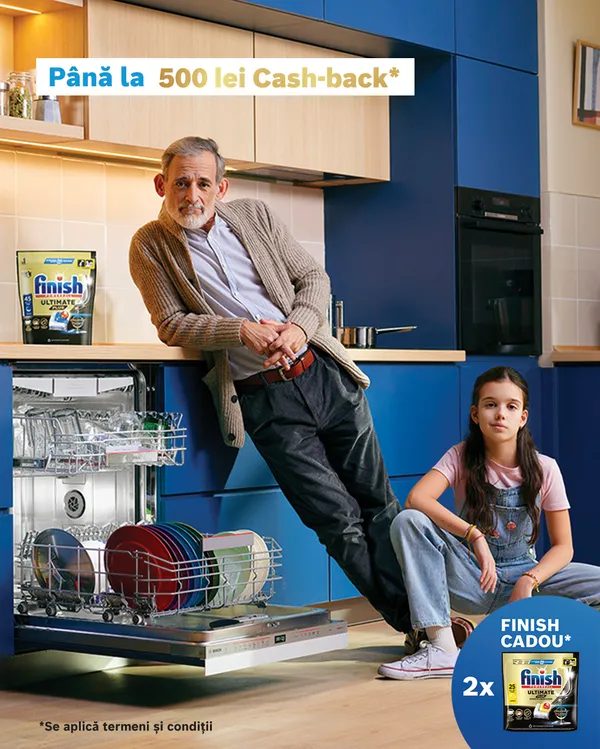 Doua persoane lângă o mașină de spălat vase încorporată, pe blatul de bucătarie pungă cu detergent de spălat vase Finish.