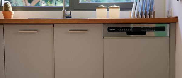 Ένα πλυντηριο πιάτων εντοιχισμένο σε κουζίνα με μπεζ πάγκους.