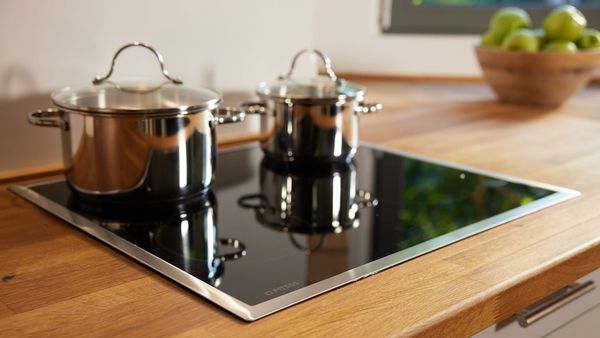 Μια εστία pitsos σε ξύλινο πάγκο κουζίνας, με δύο κατσαρόλες πάνω στα μάτια.