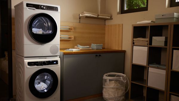 Ένα μοντέρνο με ξύλινες κατασκευές μπάνιο, δύο πλυντηρια ρούχων τοποθετημένα το ένα πάνω στο άλλο.