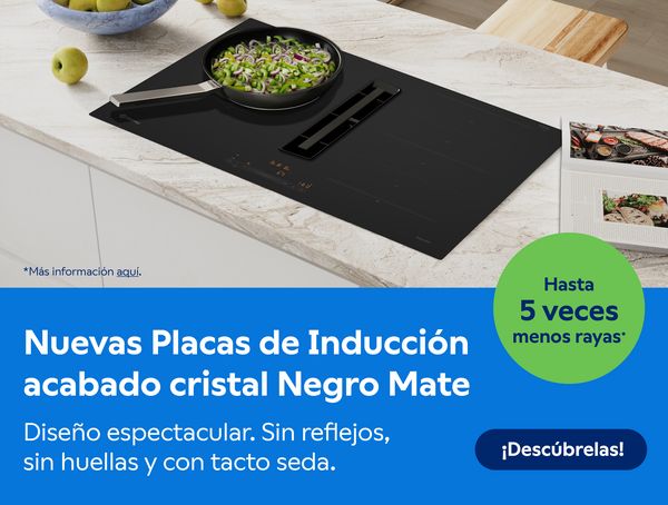 Imagen de placa cristal mate en funcionamiento sobre encimera de cocina, con una sartén con alimentos. 