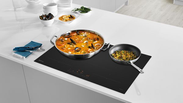 Paellera llena de comida cocinándose sobre una placa Balay 