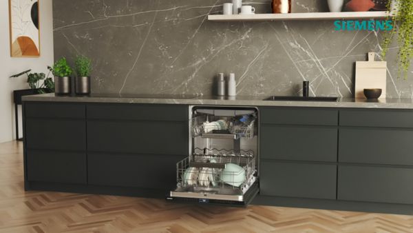 
       En elegant Siemens opvaskemaskine er &aring;ben og afsl&oslash;rer service og glas indeni, mod en moderne k&oslash;kkenbaggrund med en marmorv&aelig;g.
      