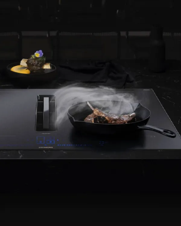 Uno spazio lavanderia Siemens con unità di lavatrice e asciugatrice impilate, circondate da vestiti sistemati ordinatamente e cesti per la biancheria.