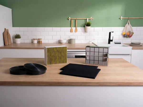 Un plan de travail de cuisine moderne présente divers filtres à air, dont un jaune et blanc, un filtre de type grille et deux tampons filtrants noirs.