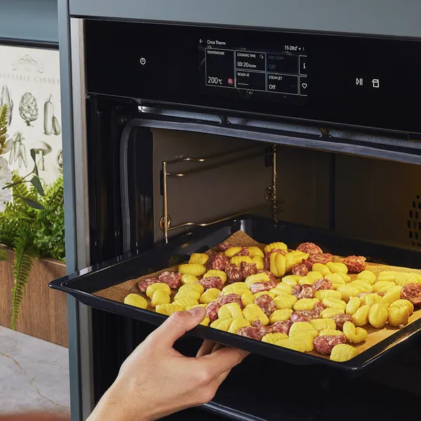 Прехвърляне на ньоките и наденицата във фурната.