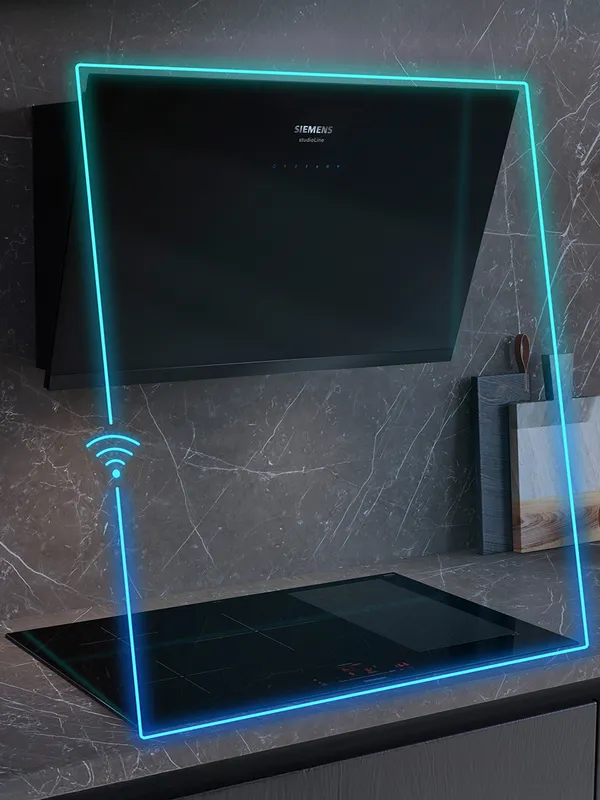 Modern kitchen features a sleek black Siemens induction cooktop with illuminated edges and a stylish hood above, set against marble walls.