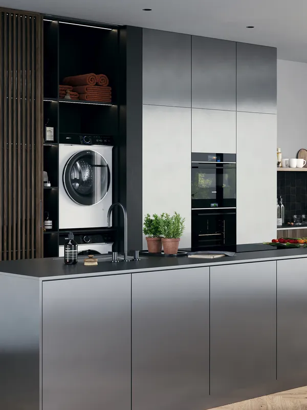 A modern kitchen with a large island, integrated Siemens appliances including a hidden laundry area with a washing machine and dryer, and built-in ovens, all featuring sleek, minimalist design.