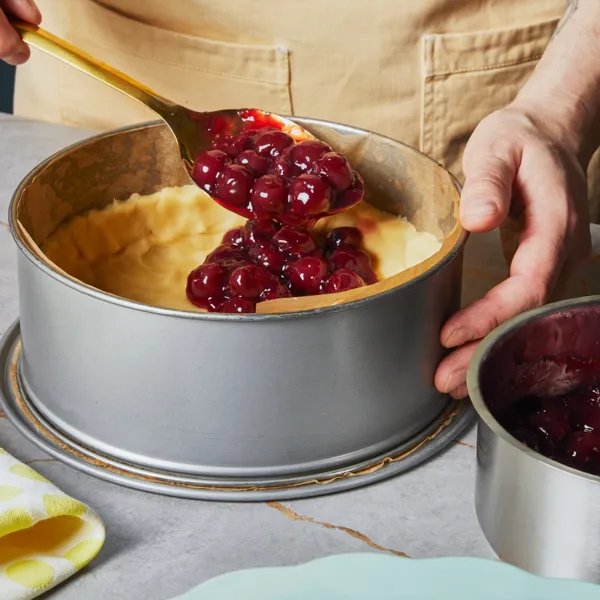 Die Sauerkirschfüllung aus dem Edelstahlkochtopf auf den Teig in der Backform gießen.