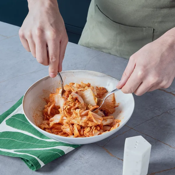 Eine Person vermengt Chinakohl mit der Gewürzpaste in einer Schüssel, um einen schnellen Kimchi herzustellen.