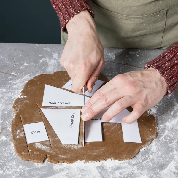 Ausgerollter Lebkuchenteig wird mithilfe von Schablonen in Formen geschnitten.