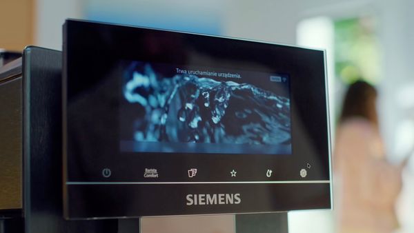 Para podziwia ekspres do kawy Siemens, korzystając z jego funkcji w nowoczesnej kuchni.