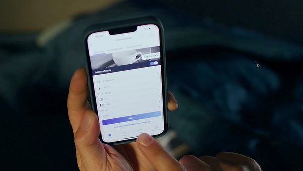 Mężczyzna relaksuje się w ł&oacute;żku, korzystając ze smartfona, podczas gdy kobieta śpi spokojnie obok niego.