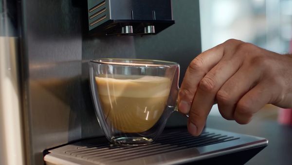 Mezczyzna w salonie, przed ekspresem do kawy