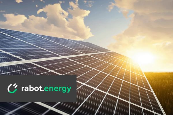 Unter strahlend blauem Himmel gl&auml;nzen die Solarpaneele, der Sonnenuntergang taucht sie in warmes Licht, und das Logo von Rabot Energy ist prominent zu sehen.