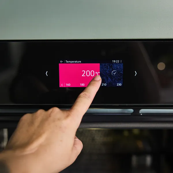 Hand setting a modern oven's digital display to 200°C.