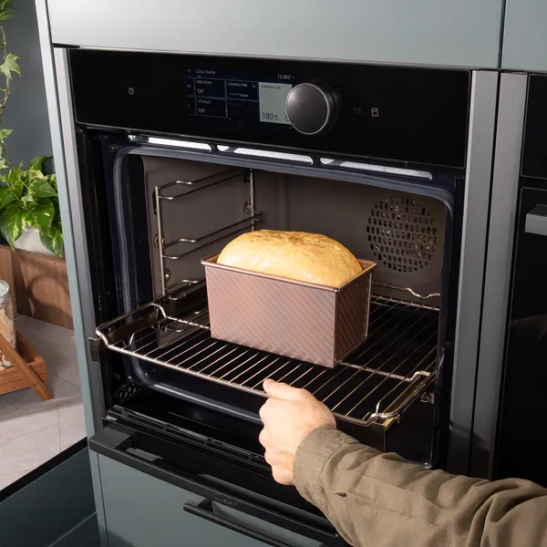 Baking bread in oven, hand placing loaf on rack, kitchen appliance, cooking, food preparation.