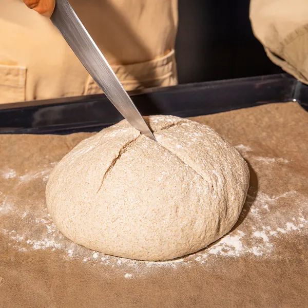 Hands kneading dough on a floured surface, preparing for baking.